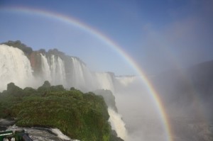 Um arco-íris bem no meio da tarde encanta os visitantes que apreciam as Cataratas